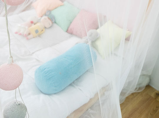 A child's bed covered with a mosquito net.